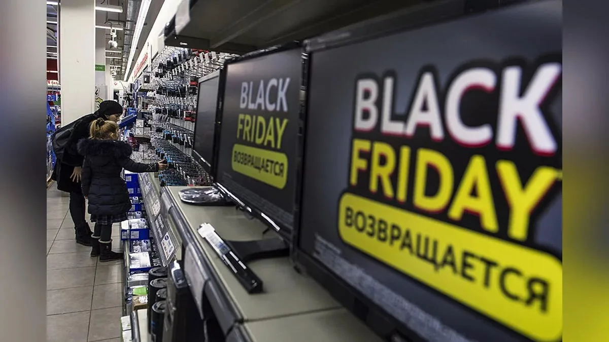 Family browsing televisions with Black Friday ads in an electronics store aisle