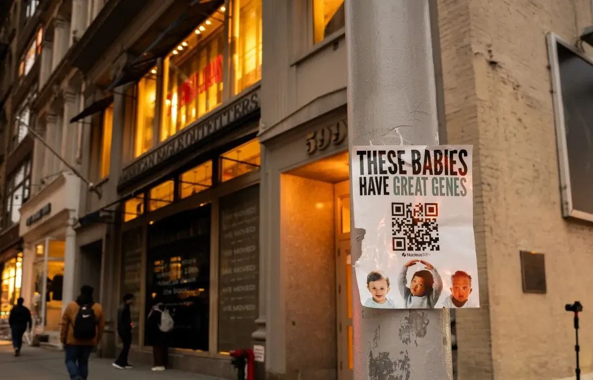 Urban street scene with a poster on a lamppost featuring the text “THESE BABIES HAVE GREAT GENES” and a QR code