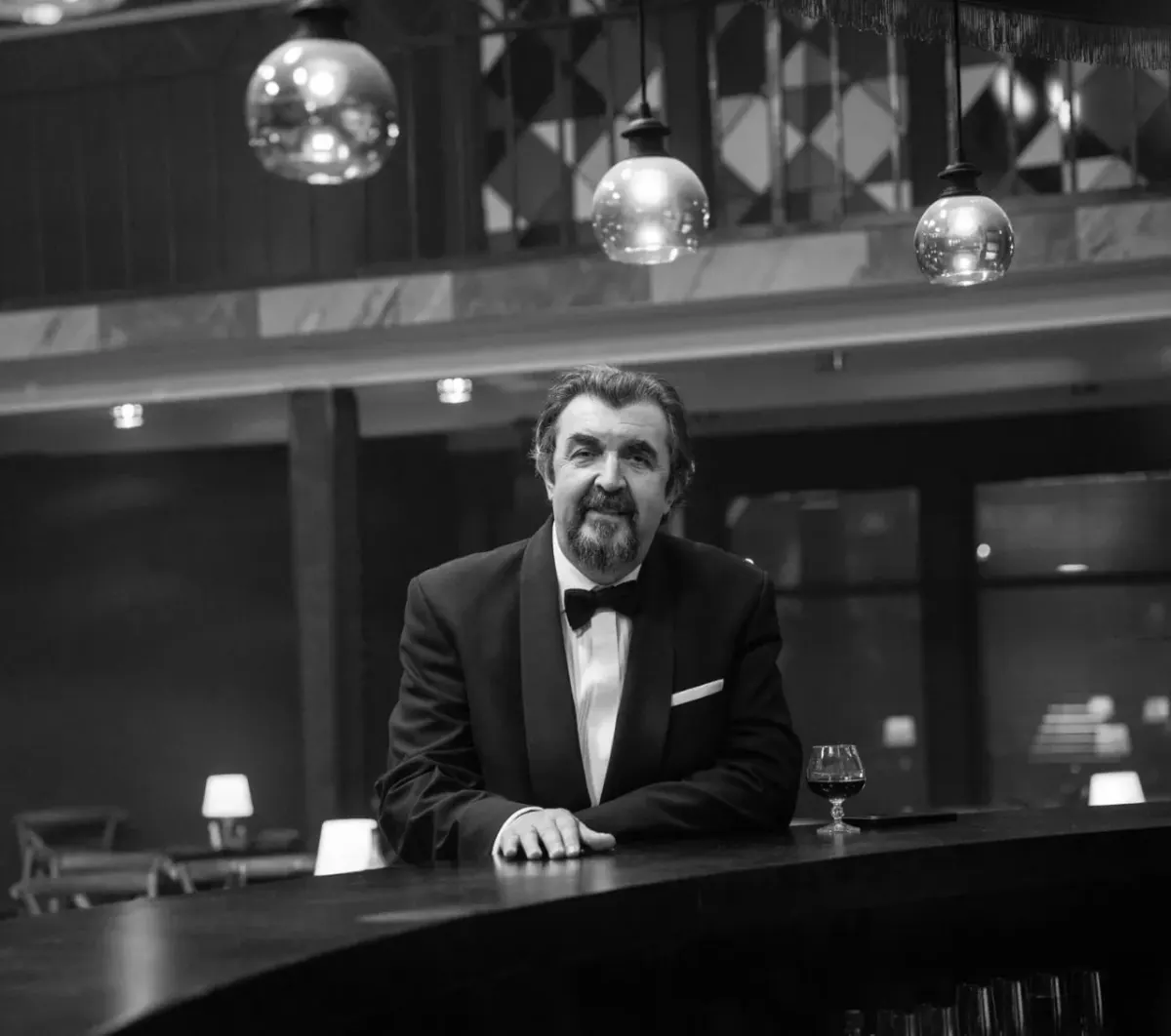 Man in tuxedo at bar counter in black and white, suggesting a professional service choice