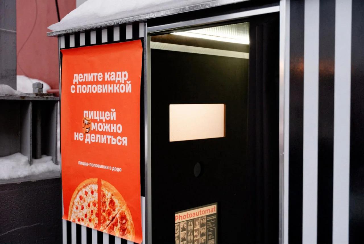 Snowy street storefront with Russian pizza advertisement poster beside a dark doorway Snowy street storefront with Russian pizza advertisement poster beside a dark doorway